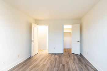A bedroom with hardwood floors and white walls